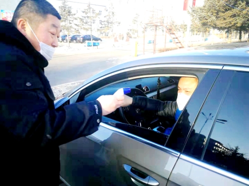图为东荣二矿保卫科干警严格检查进出矿车辆，，，，，，，对每名进矿职工都进行体温测量并登记。。。。。。。。